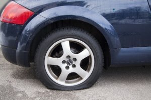 a photograph of a flat tire on a dark blue vehicle