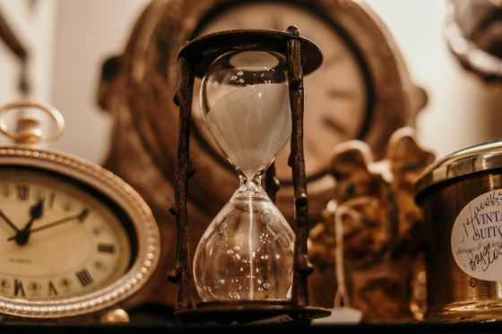 an hourglass running out of time and two clocks