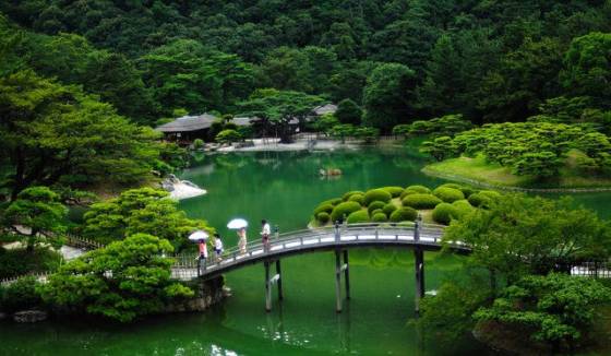 Beautiful garden in Japan with pond and lush green foliage.