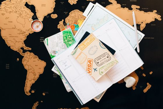 a travel visa laying on top a scheduler and world map