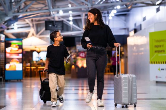 two minors traveling through an airport with luggage and passports