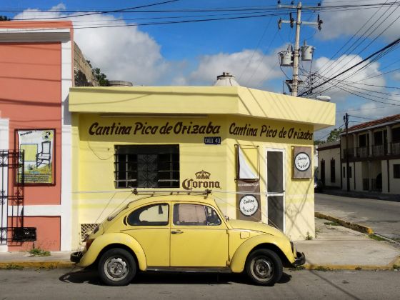 A yellow Volkswagen Beetle parked in front of a Mexican cantina