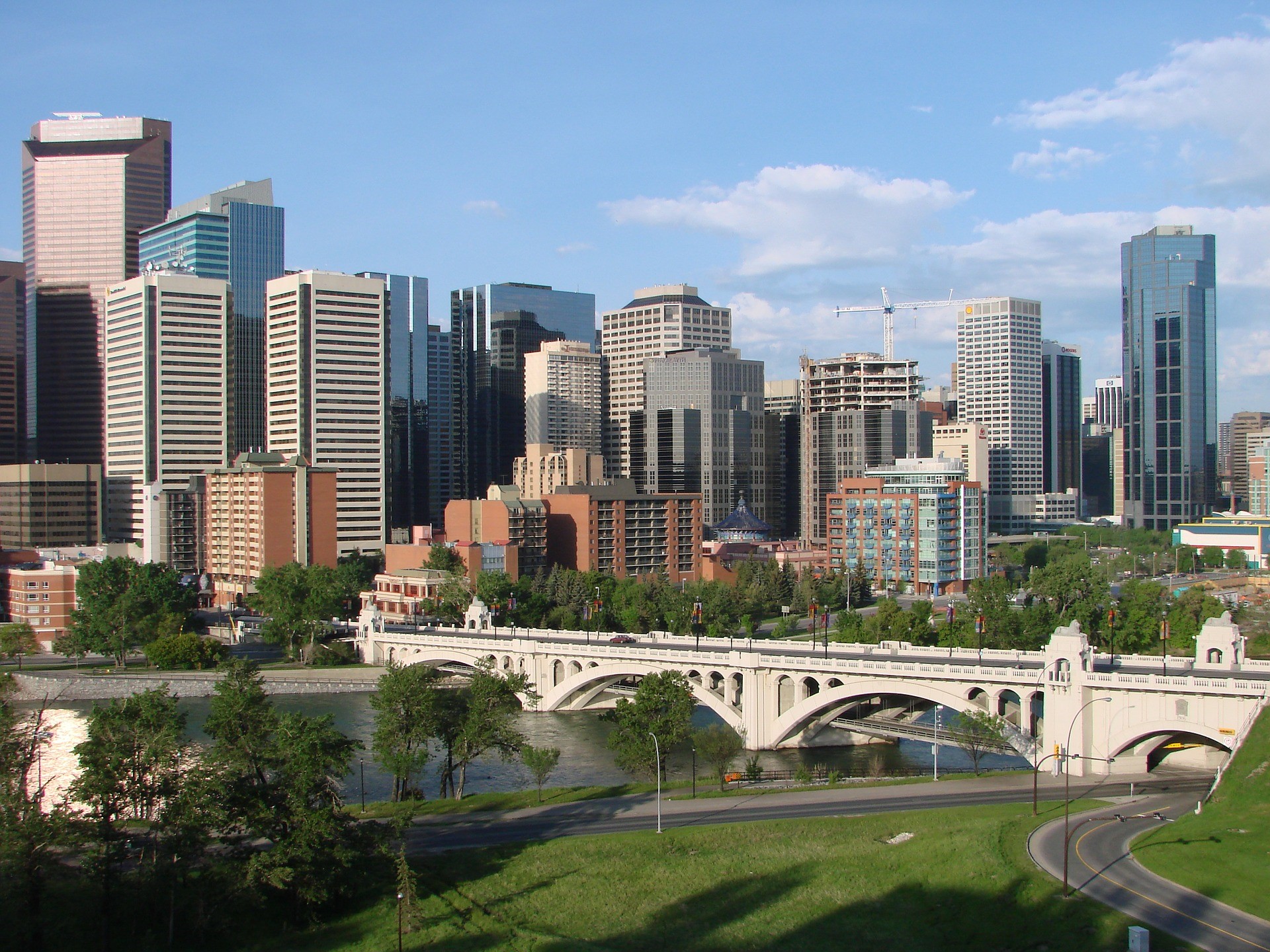 a daytime view of the Calgary, Alberta skyline and a pedestrian bridge over the Bow River