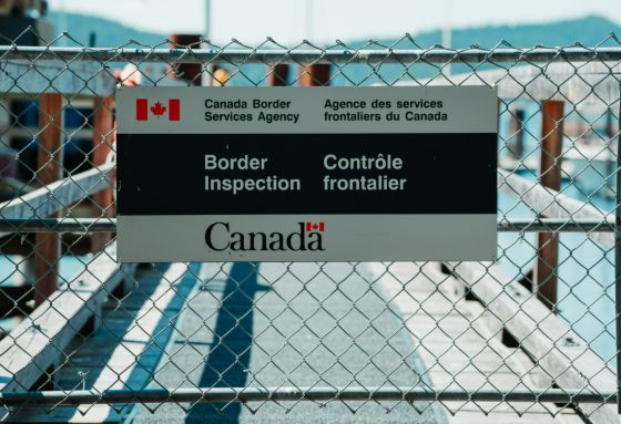 A Canadian border inspection sign on a chain link fence