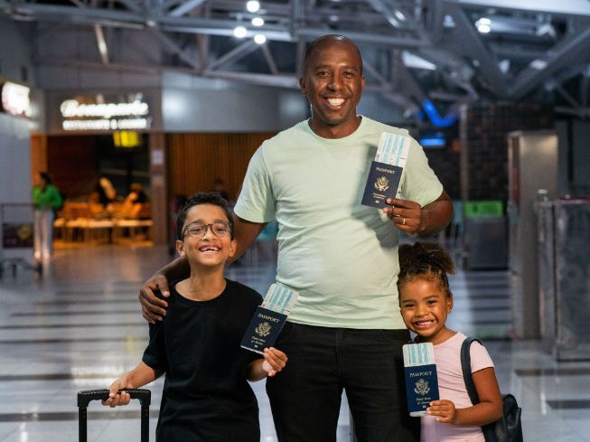 father with two minor children holding passports and boarding passes at airport