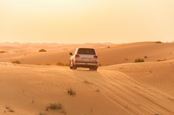 an SUV drives across a North African desert