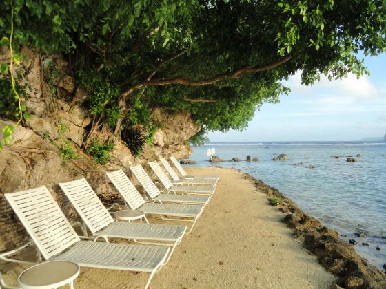 Beach chairs on a Guam beach under tree cover