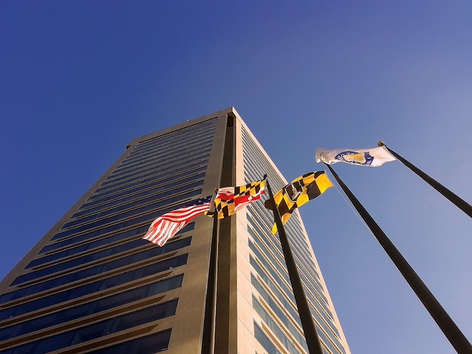 maryland state flags with tall building in the background.
