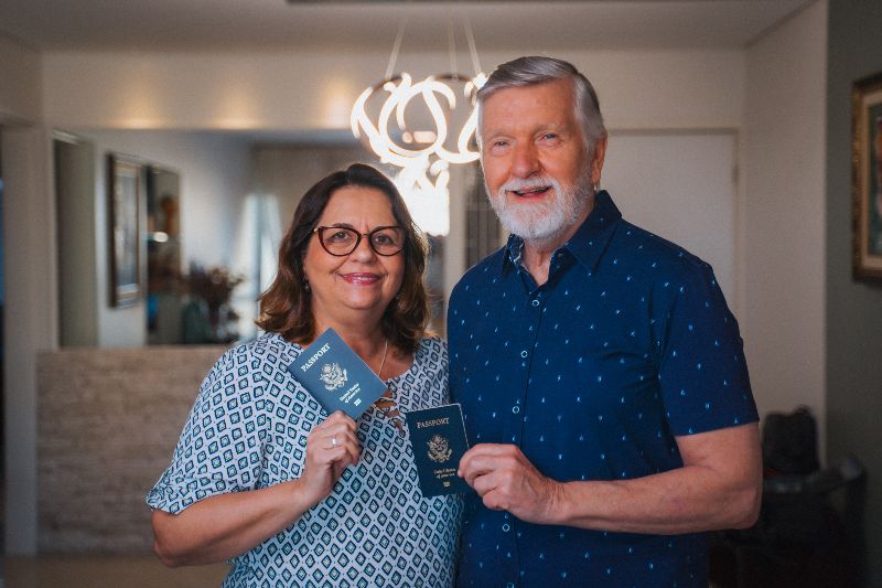 A smiling older couple holding their passports