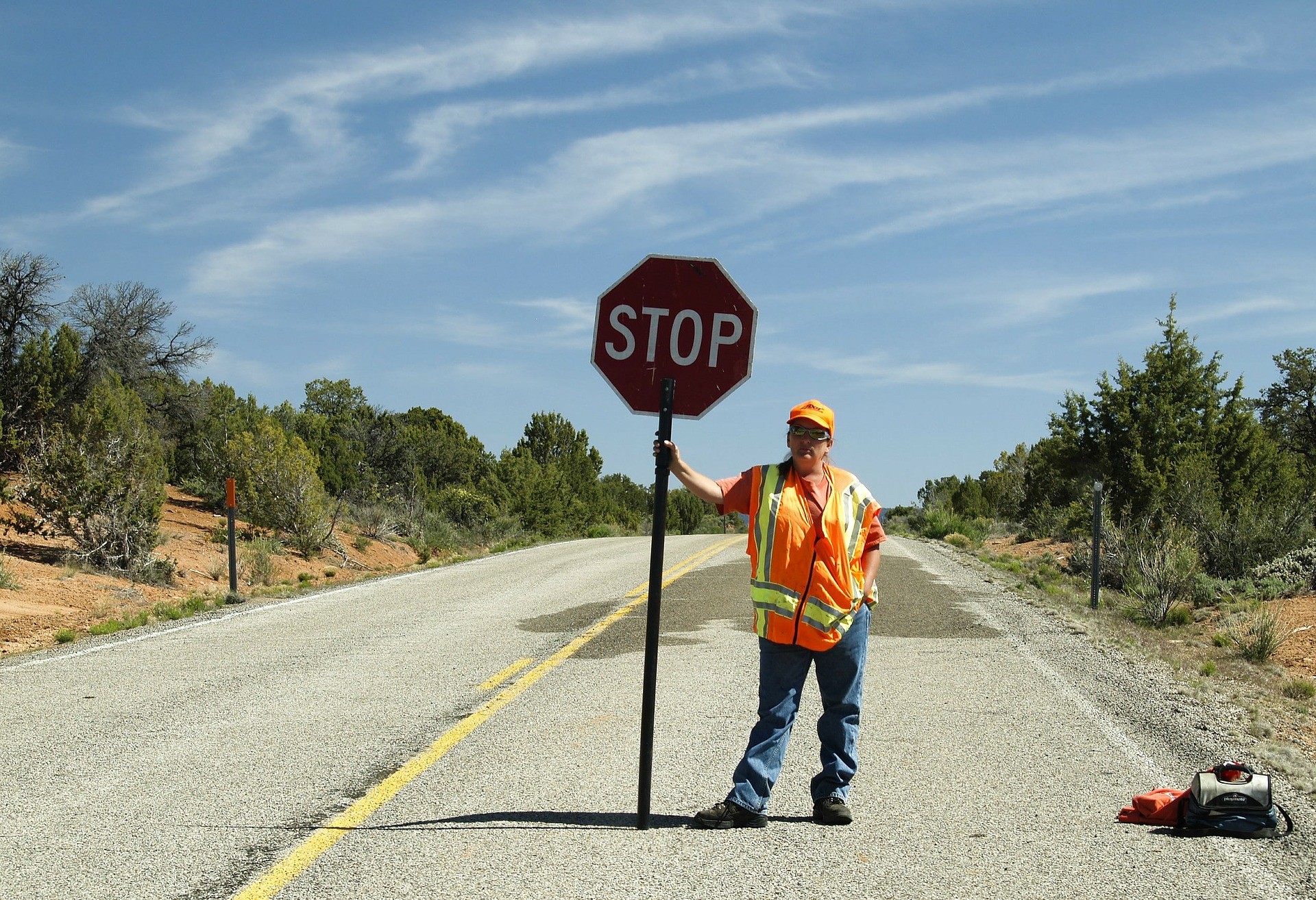 a construction flag man holding a stop sign in the middle of an empty road