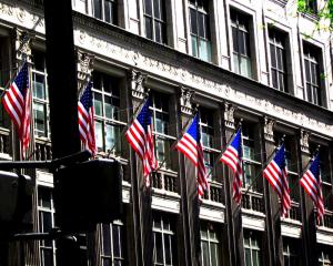 Several USA flags flying on building in NYC.