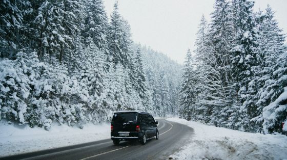a van driving alone on a curvy, snowy road in Canada