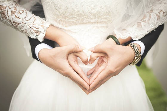 Bride and Groom make hearts at wedding