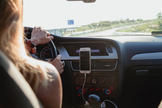 A woman driving in a rental car with an international driving permit on a country road abroad