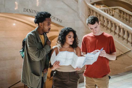 3 20-somethings looking at a map at a train station