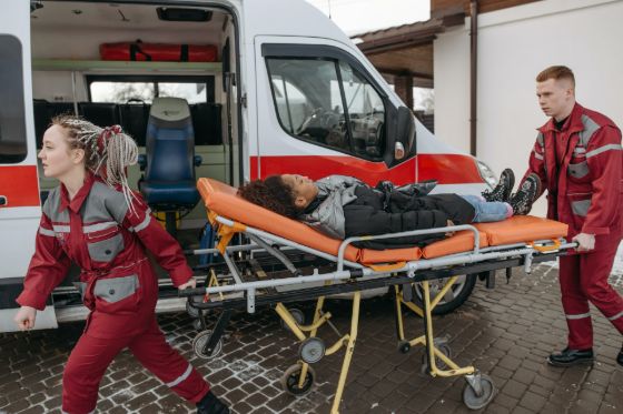 EMTs with a patient on a stretcher in front of an ambulance