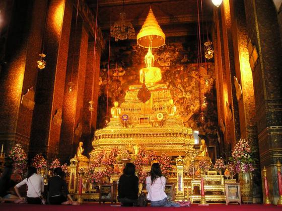 Brightly lit gold alter inside a Buddhist Temple in Bangkok, Thailand