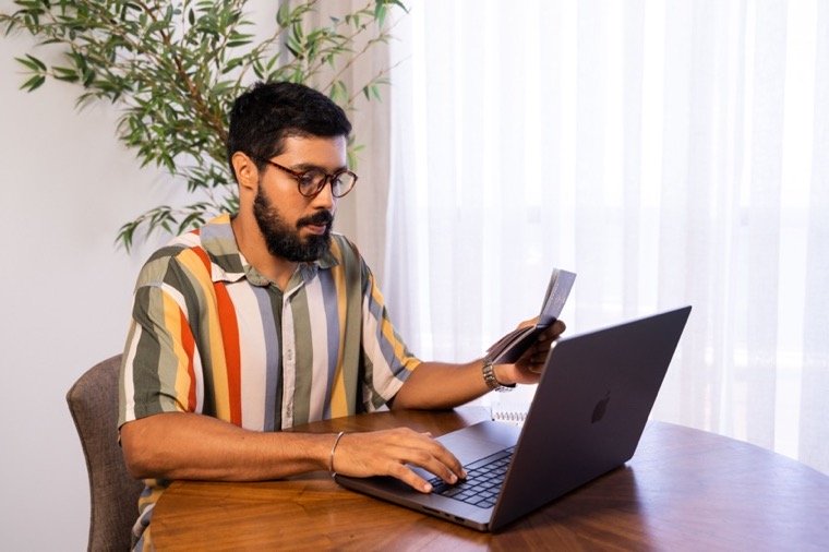 man holding a passport researching passport expeditors at a laptop