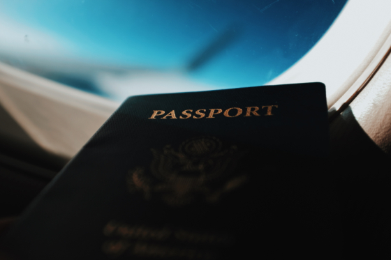 a passport on a lap in front of a plane window
