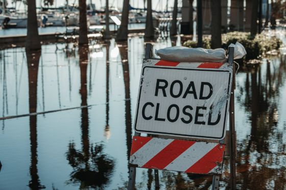 a road closed sign in front of a hurricaine-flooded road