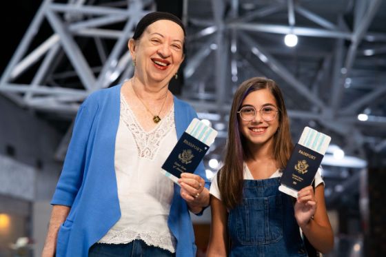 Senior citizen and young girl holding renewed passports and boarding passes at airport