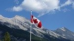 Canadian flag flying with mountains in background.